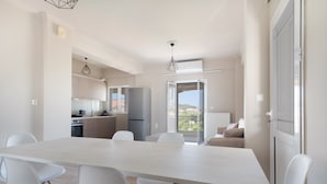 A modern kitchen with white cabinets, a refrigerator, and a dining area with a table and chairs. - Apartment 'Almyra' with Sea View, Wi-Fi and Air Conditioning (Lefkada)