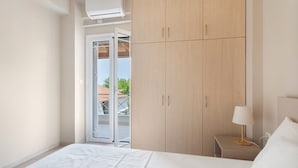 A bedroom with a bed, a nightstand, a lamp, a wardrobe, and a sliding glass door leading to an outdoor area. - Apartment 'Almyra' with Sea View, Wi-Fi and Air Conditioning (Lefkada)