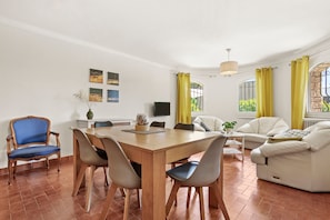 Una sala de estar moderna con comedor, paredes blancas y cortinas amarillas.