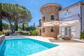 A pool with lounge chairs, a stone tower, and a building with a balcony. - Apartment '80m² Dans Villa' with Shared Pool, Shared Terrace and Wi-Fi (Fréjus)