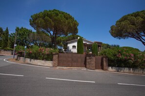 A gated residential area with a house, a curved road, and trees.