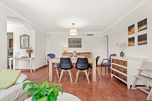 Un salon moderne comprenant un coin repas, un canapé blanc, une table basse et une plante en pot.
