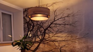 A room with a wooden table, a potted plant, a decorative wall, and a hanging light fixture.