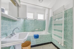 Une salle de bain équipée d’un lavabo, d’une baignoire et d’un porte-serviettes.