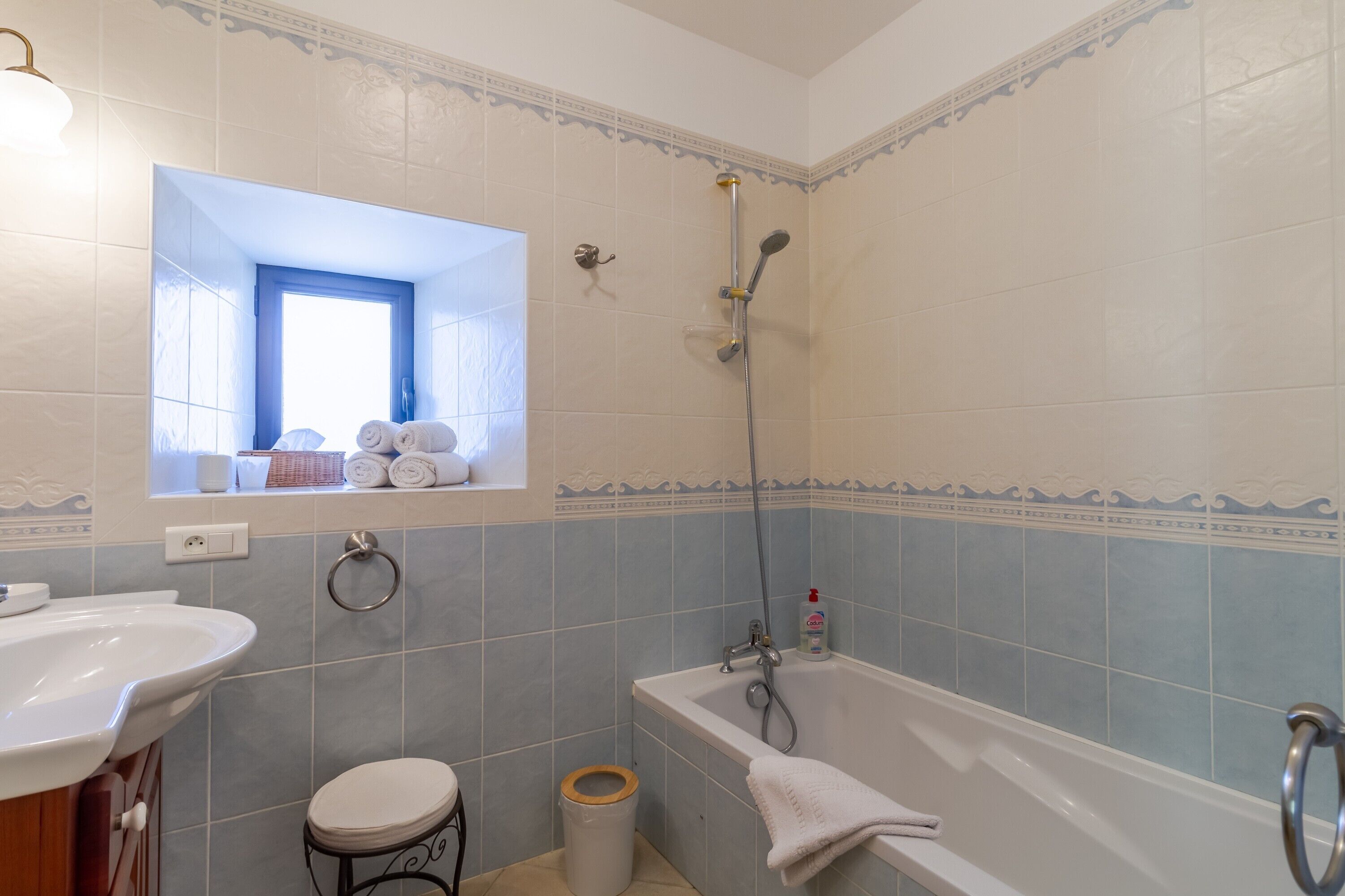 Ein Badezimmer mit Badewanne, Toilette, Waschbecken und einem Fenster mit Handtüchern.