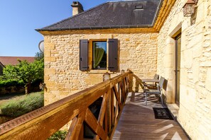 A stone building with a wooden deck, a window with shutters, and a door. - Clémentine Room – Romance & Comfort – Shared Pool (Proissans)