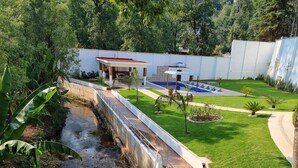 A modern house with a swimming pool, a paved deck, and a well-maintained garden.