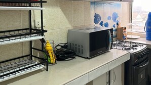 Une cuisine moderne dotée d’armoires en bois, d’un four à micro-ondes, d’une cuisinière à gaz et d’un four encastré.