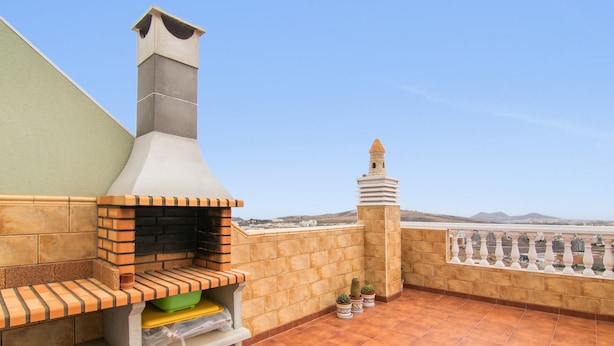 A rooftop terrace with a brick oven, potted plants, and a decorative tower. - Holiday Home 'El Atico' with Sea Views, Private Terrace and Wi-Fi (Las Palmas)