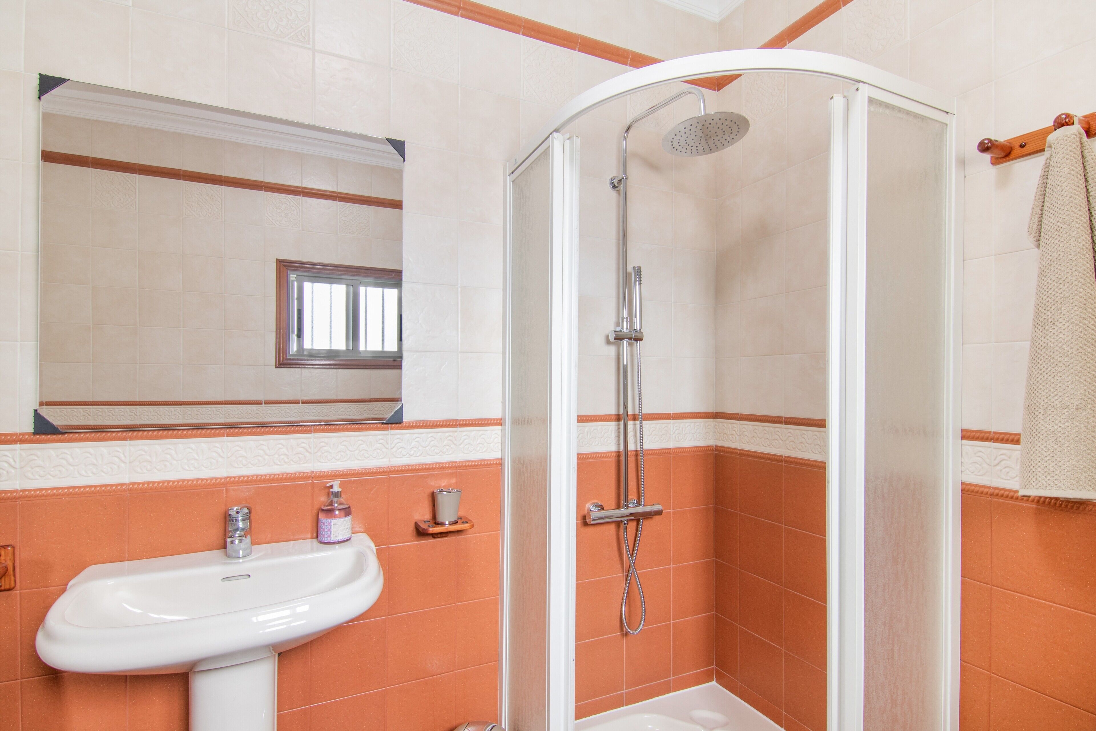Un baño con ducha, lavamanos y espejo.
