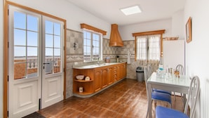 A kitchen with a central island, a dining table with chairs, and a view through the windows. - Holiday Home 'El Atico' with Sea Views, Private Terrace and Wi-Fi (Las Palmas)