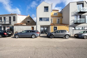 A parking lot with three cars parked in front of a building with a flat roof and a balcony. - Apartment 'Ria' with Wi-Fi and Air Conditioning (Aveiro)