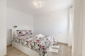 Un dormitorio moderno con cama, paredes blancas y una lámpara en el techo.
