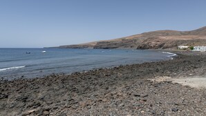 A rocky beach with a clear view of the sea and distant hills.
