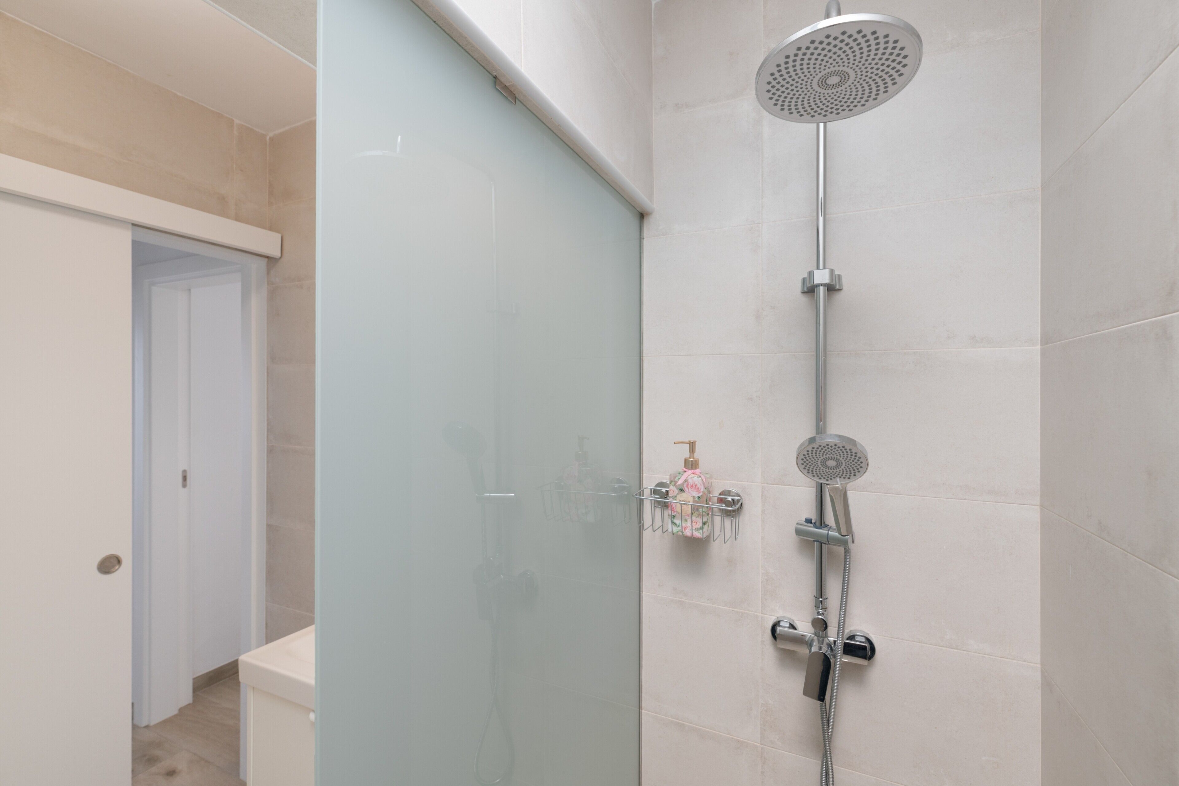Une salle de bain moderne avec une douche à parois de verre, des toilettes blanches et un lavabo blanc.