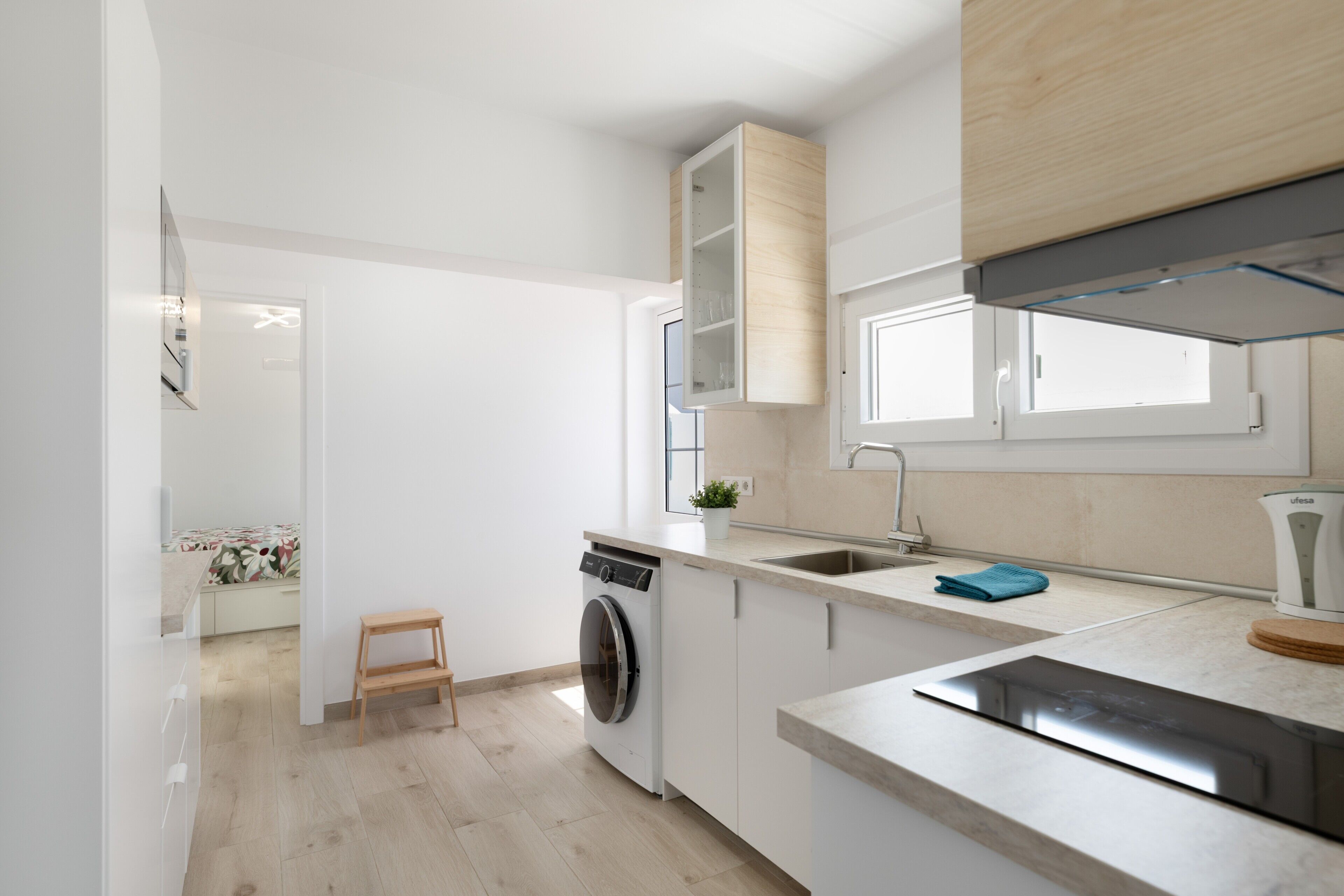 Una cocina moderna con lavadora, pileta y ventana.