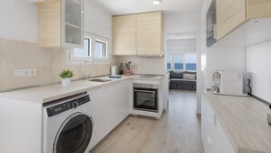 A modern kitchen with a built-in washing machine, an oven, and a coffee maker.