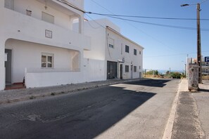 A two-story building with a white facade, a visible balcony, and a clear sky. - Holiday Home 'Flôr' with Sea View, Private Terrace and Wi-Fi (Albufeira)