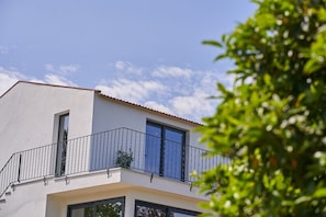 Un bâtiment moderne doté d’un balcon, de grandes fenêtres et surplombant un ciel dégagé.