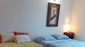 A room with two beds, a wall-mounted painting, and a bedside lamp.