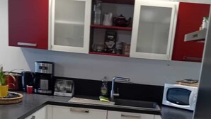 A compact kitchen with white cabinets, a microwave, a coffee maker, and a sink.