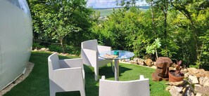 Een klein terras met een tafel en stoelen, omringd door groen en uitzicht op het landschap.