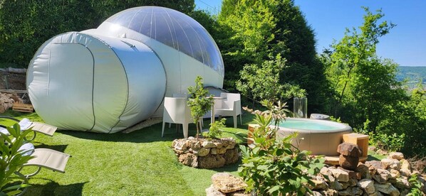 Een geodetische koepelconstructie met een jacuzzi en een zitgedeelte buiten.