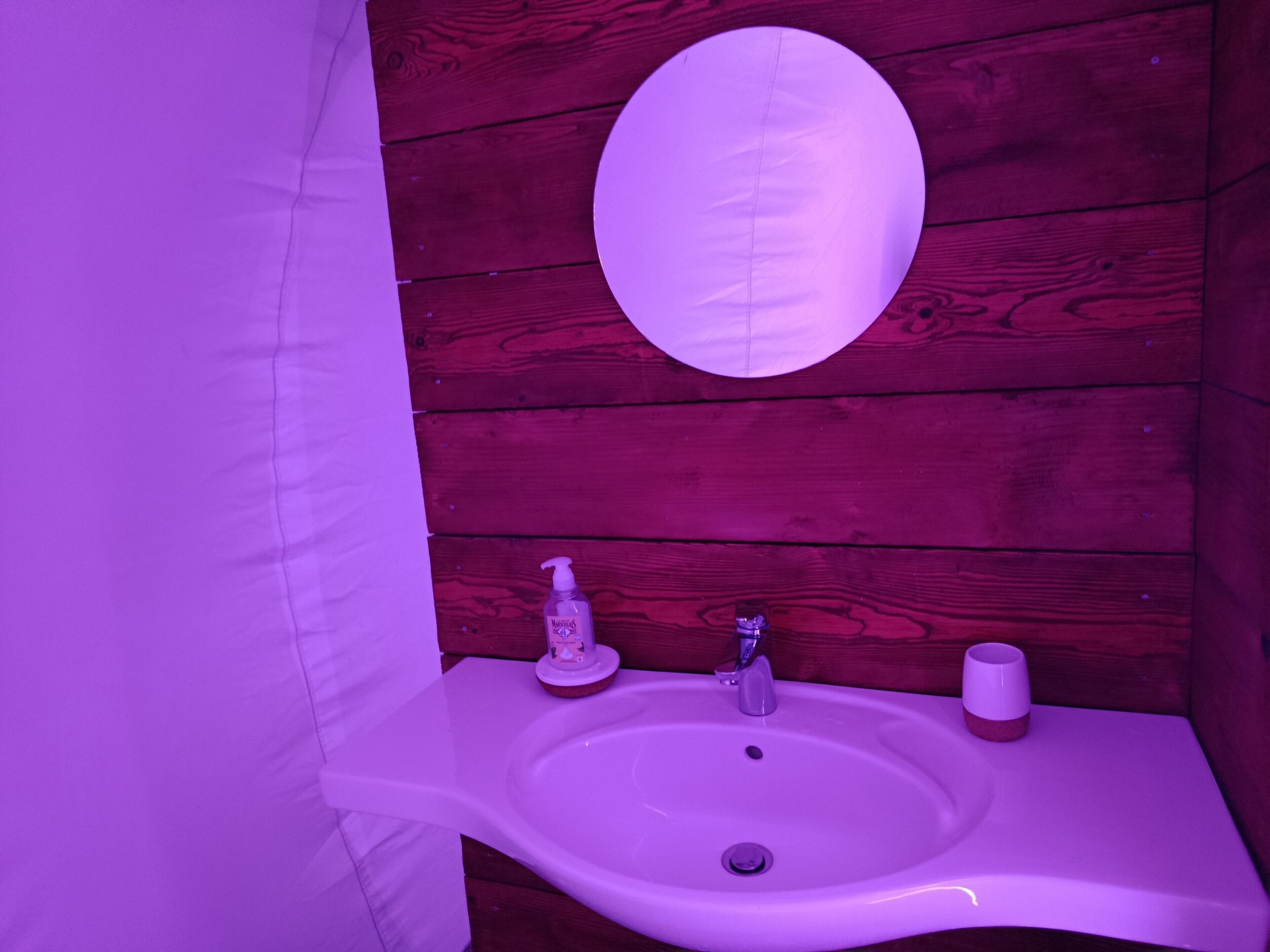 Un bagno con lavandino bianco, uno specchio e una parete in legno.