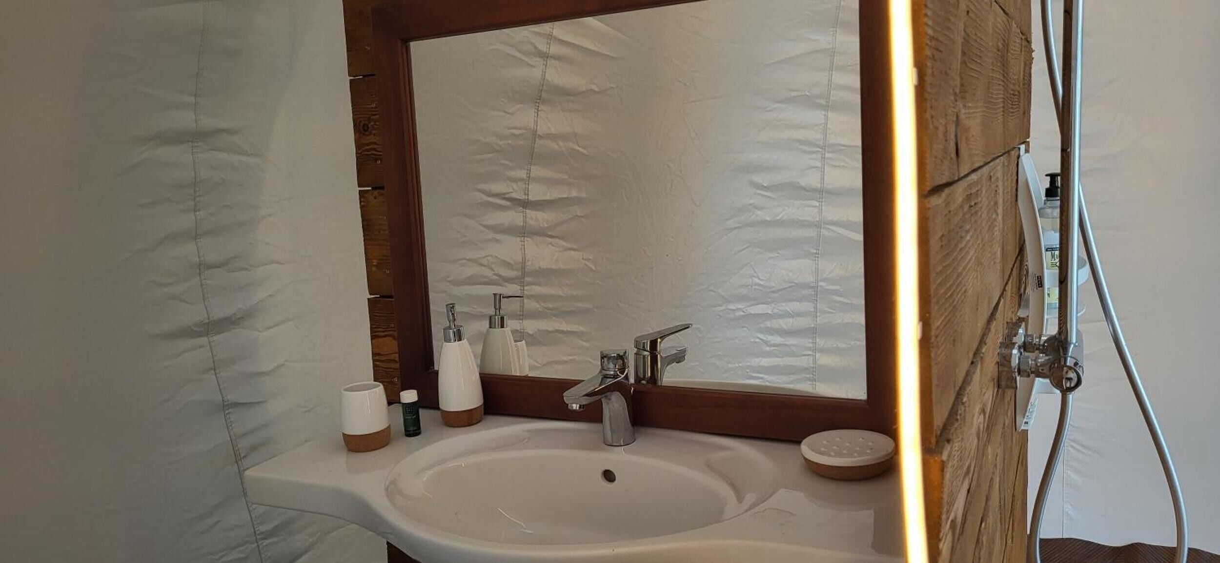Een badkamer met een witte wastafel, een spiegel en een douche.
