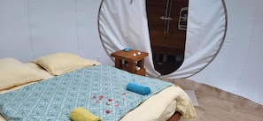 A bed with a patterned bedspread, pillows, and rolled towels.