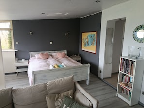 A bedroom with a bed, bedside tables, a bookshelf, and a window.