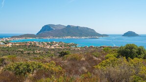 Un pueblo costero con una montaña destacada, mar azul cristalino y vegetación densa.