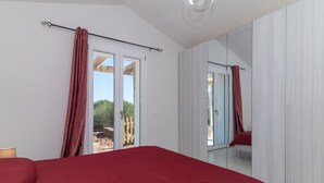 Un dormitorio con una cama grande, una puerta corrediza de vidrio, un armario y un espejo.
