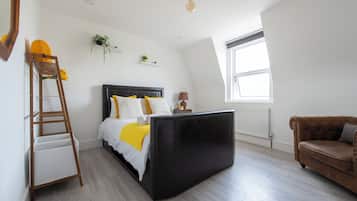 A bedroom with a bed, a ladder, a sofa, a window, and a radiator.