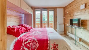 Un dormitorio con una cama, un televisor y una pared de madera.