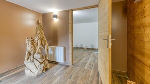 Una habitación con piso de madera, una estatua, un radiador y una puerta de madera.