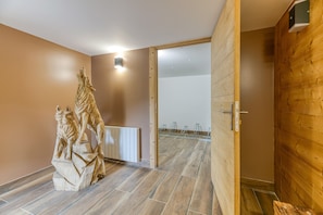 Une pièce avec un plancher en bois, une statue, un radiateur et une porte en bois.