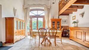 A dining area with a table and chairs, wooden cabinets, and a staircase.