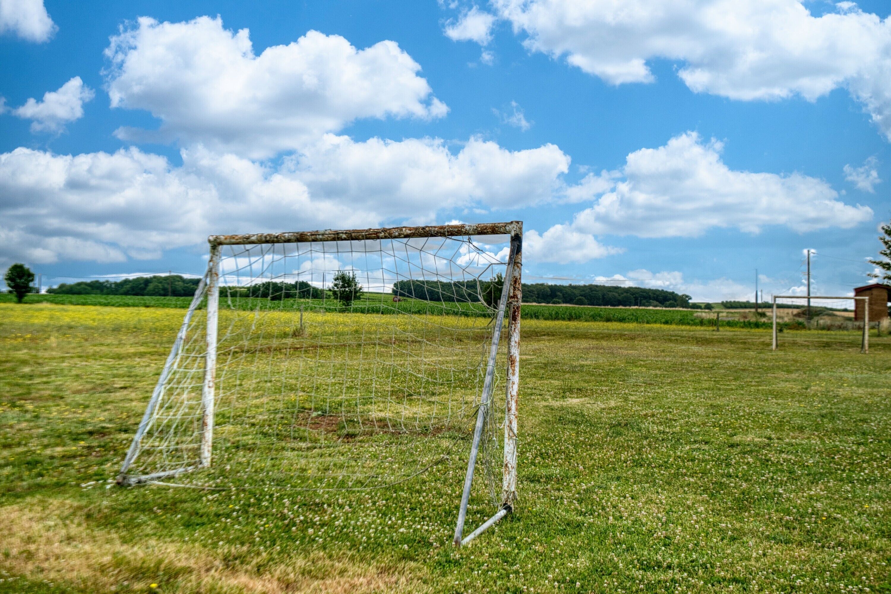A soccer goal in a grassy field with a clear sky.