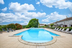 A swimming pool with lounge chairs, a stone building, and a tree in the background. - La Ferme – Family Cottage with Pool and Large Garden near Bergerac (Razac-d'Eymet)