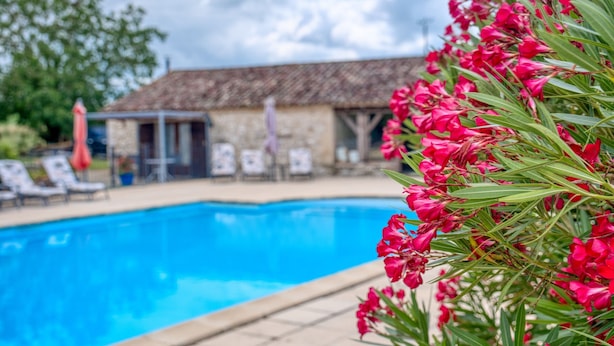 A swimming pool with lounge chairs and a building in the background.