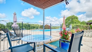 A covered outdoor seating area with a pool, chairs, and a table.