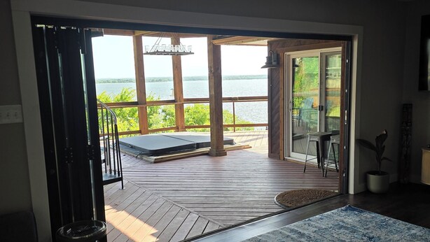 Un amplio salón con un ventanal grande que da a una terraza y un cuerpo de agua.