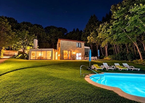 A residential property with a swimming pool, lounge chairs, and a well-lit house at night. - CASA DO LAVADOURO, overlooking the Douro River! (Paços de Gaiolo)