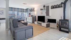 A modern living room with a sofa, TV, fireplace, and decorative items. - Villa 'Praia Azul Beach and Sun' with sea view, private garden, and Wi-Fi access (Silveira)