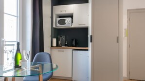 A compact room with a glass table, a chair, a microwave, a small fridge, and a window with curtains. - Relax & Recharge: Elegant Home With Sauna (Le Mans)
