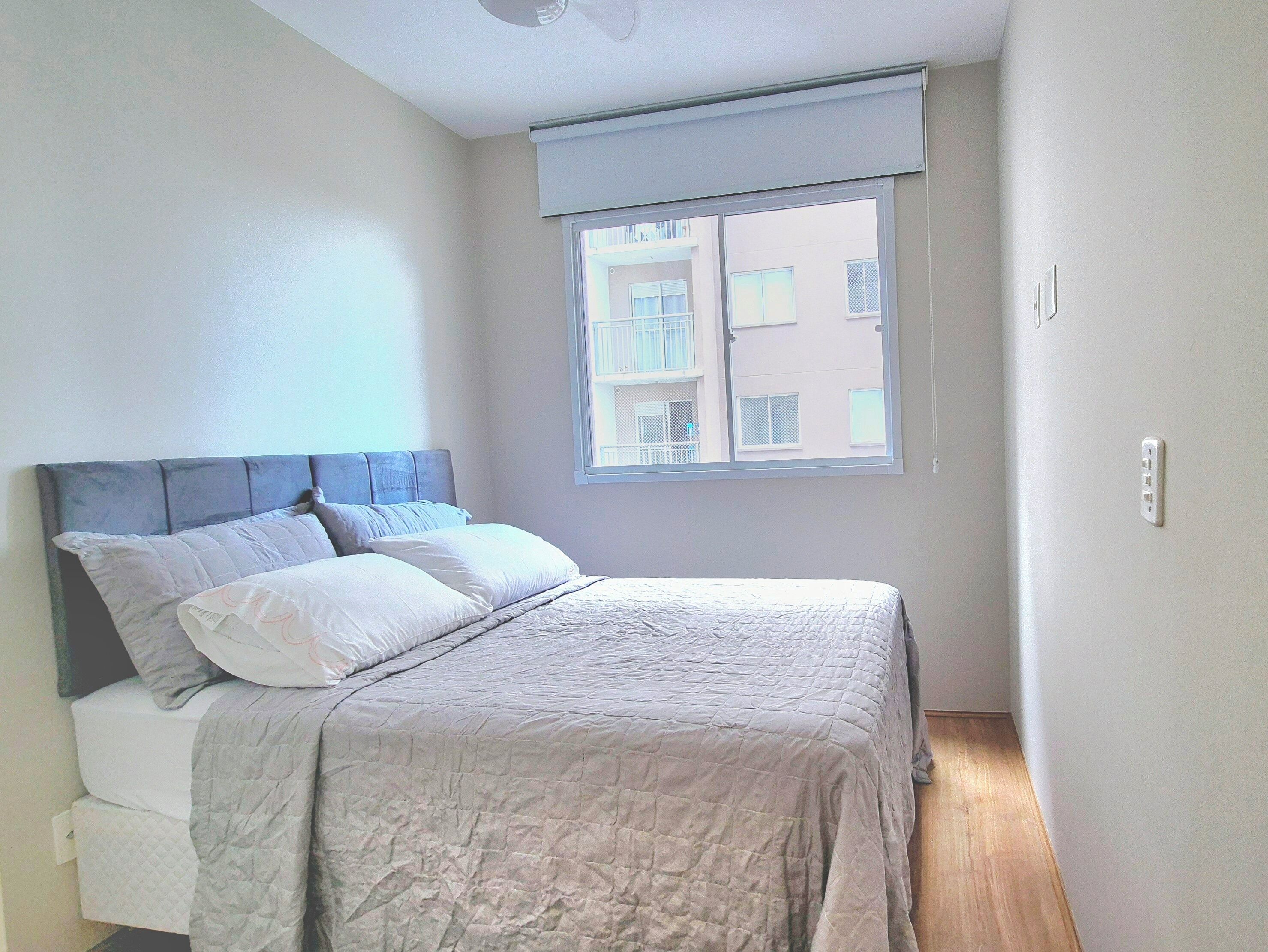 A bedroom with a bed, a window, and a ceiling fan.