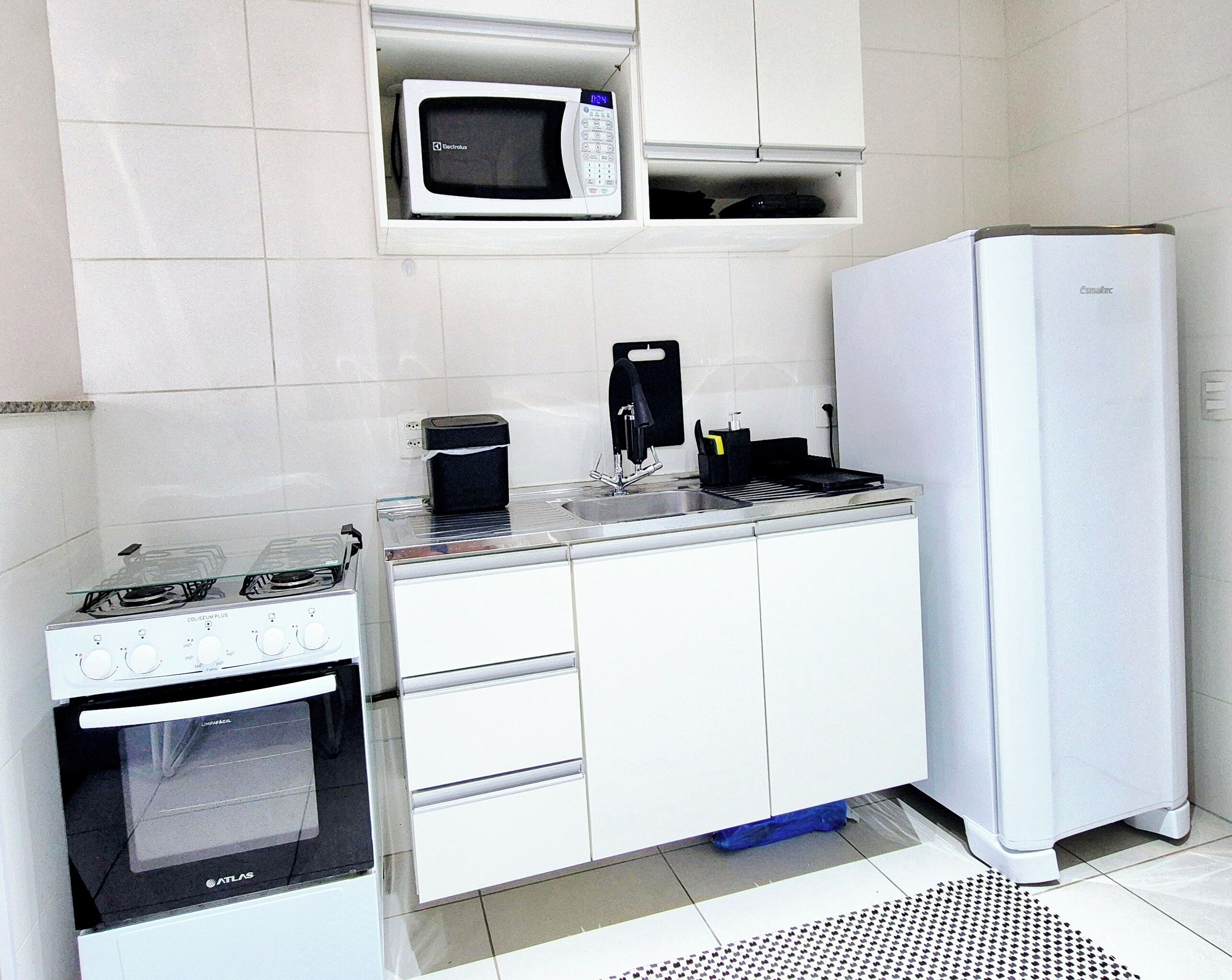 A compact kitchenette with a stove, microwave, and refrigerator.