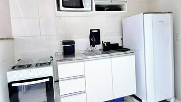 A compact kitchenette with a stove, microwave, and refrigerator.