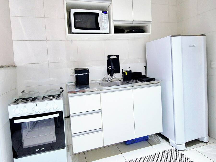 A compact kitchenette with a stove, microwave, and refrigerator.